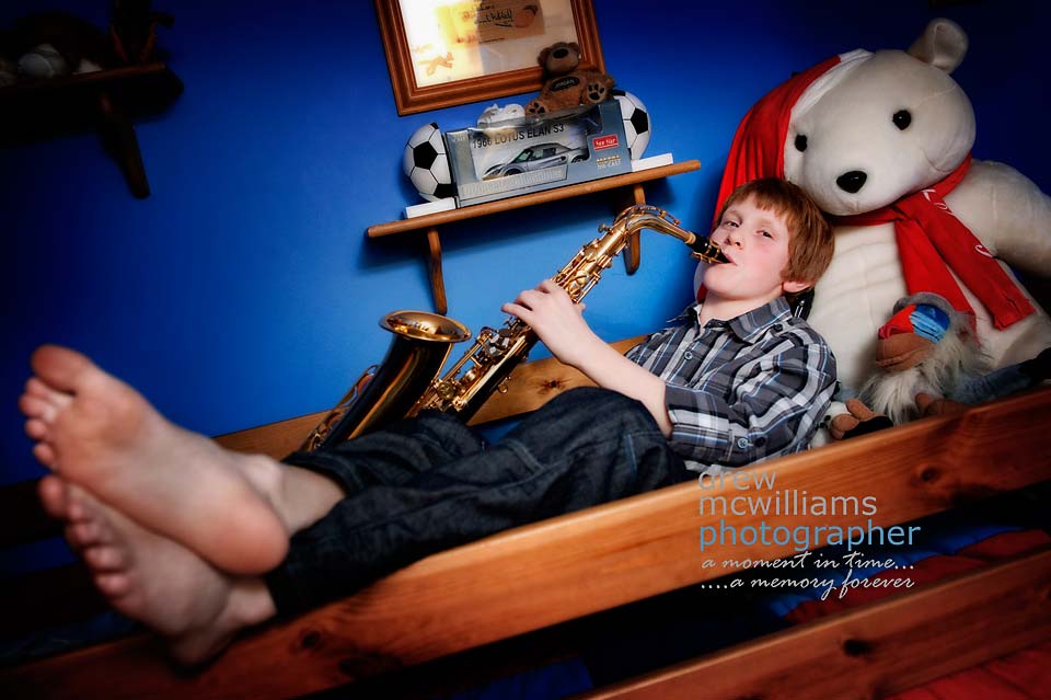 Young boy lying on bed playing clarinet